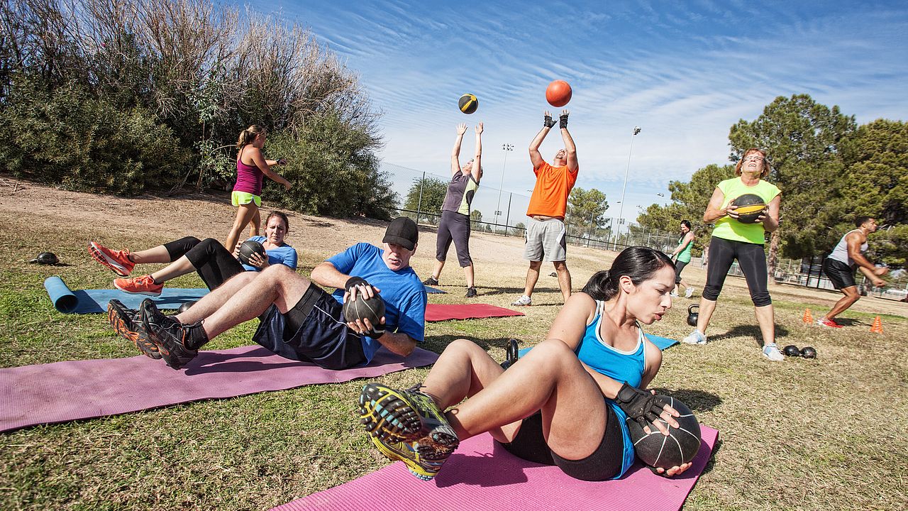 Auf dem Bild sind mehrere Personen zu sehen, die Outdoor verschiedene Functional Fitness-Übungen machen.
